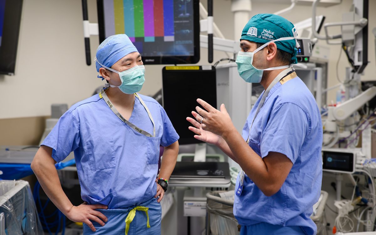 Dr. Seo and Dr. Kothari in scrubs in a robotic operating room